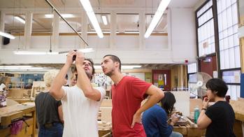 Two students examine a piece of metalwork in the Metcalf furniture studio. 