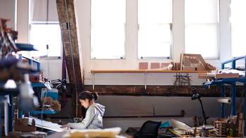 Student in a gray hoodie working at a desk in an architecture studio.