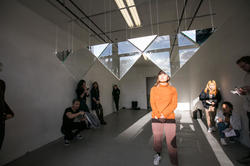 A group of students are observing a suspended artwork.