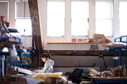 Student in a gray hoodie working at a desk in an architecture studio