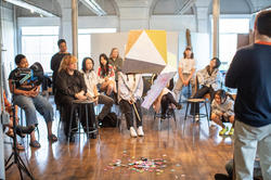 An undergraduate class of RISD students observe a piñata style artwork.
